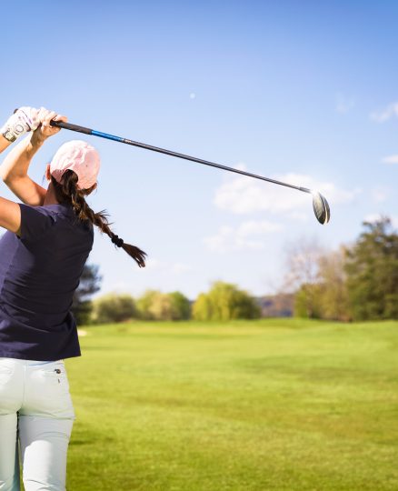 Woman golf player teeing off.
